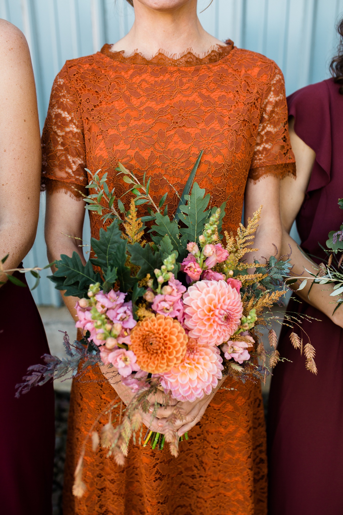 Bridesmaid in orange lace dress with dahlia bouquet