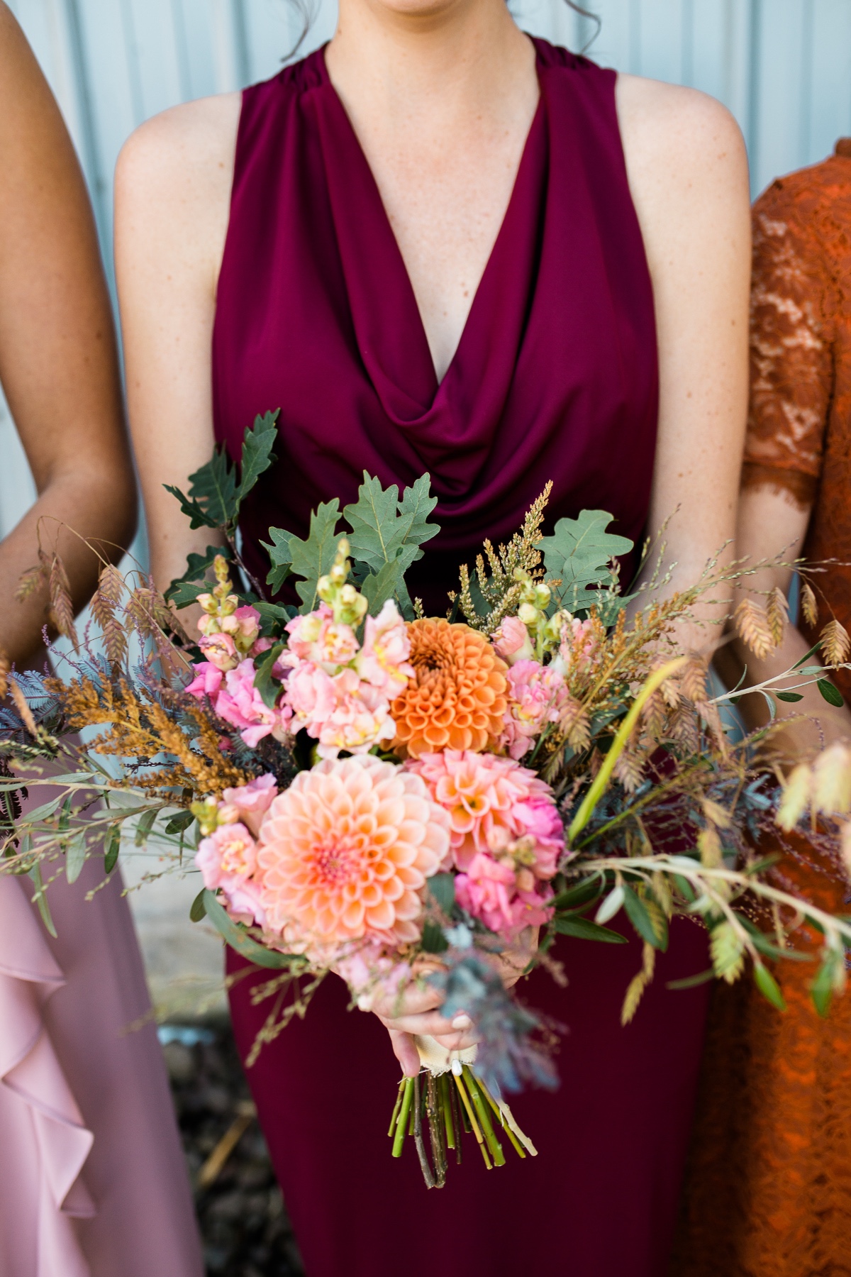 Bridesmaid holding dahlia bouquet in burgundy dress