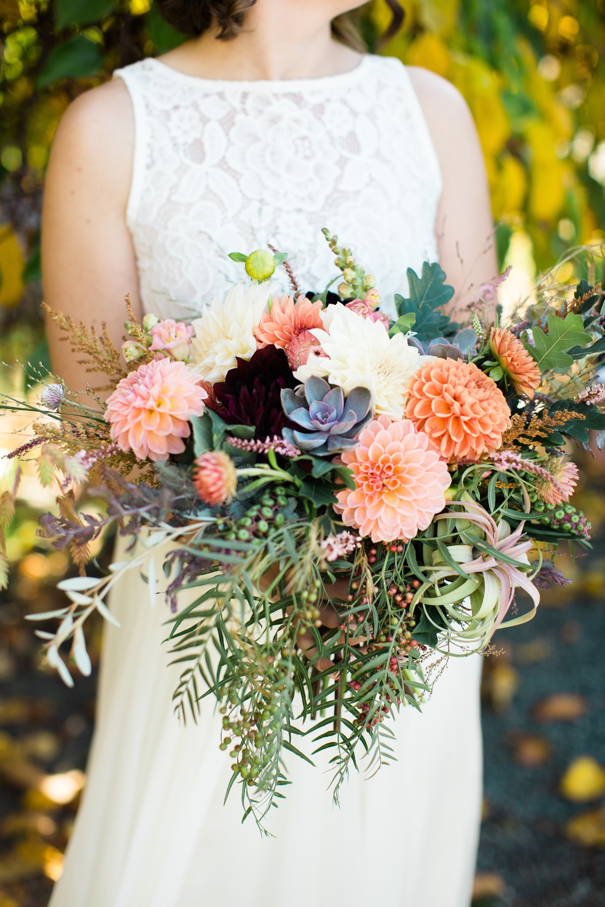 Bride holds dahlia and succulent filled wedding bouquet