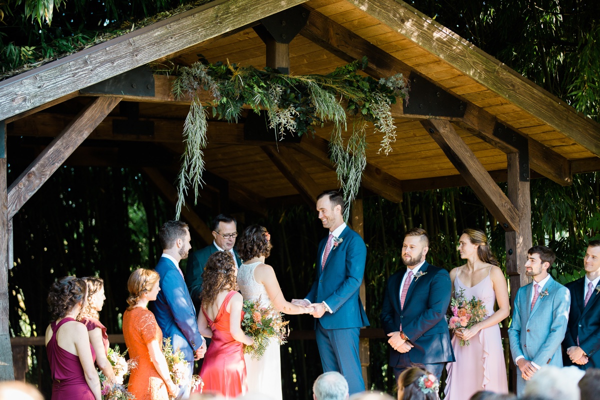 Outdoor wedding ceremony under rustic wooden arbor
