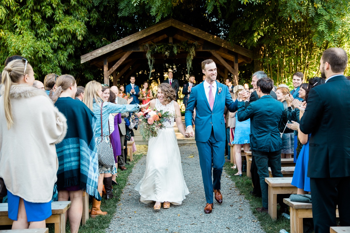 Happy couple exiting wedding ceremony, cheered by guests