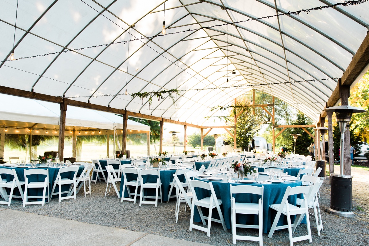 Outdoor wedding reception with teal tablecloths and white chairs