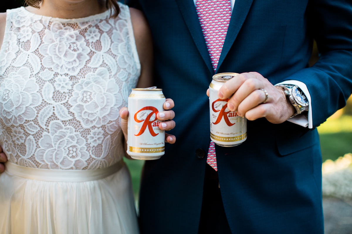 Bride and groom holding Rainier beer at wedding reception