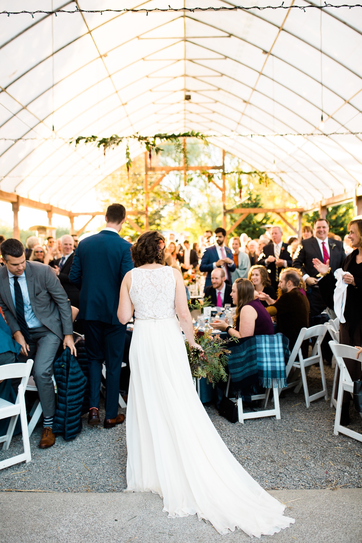 Bride walks aisle at tented outdoor wedding reception