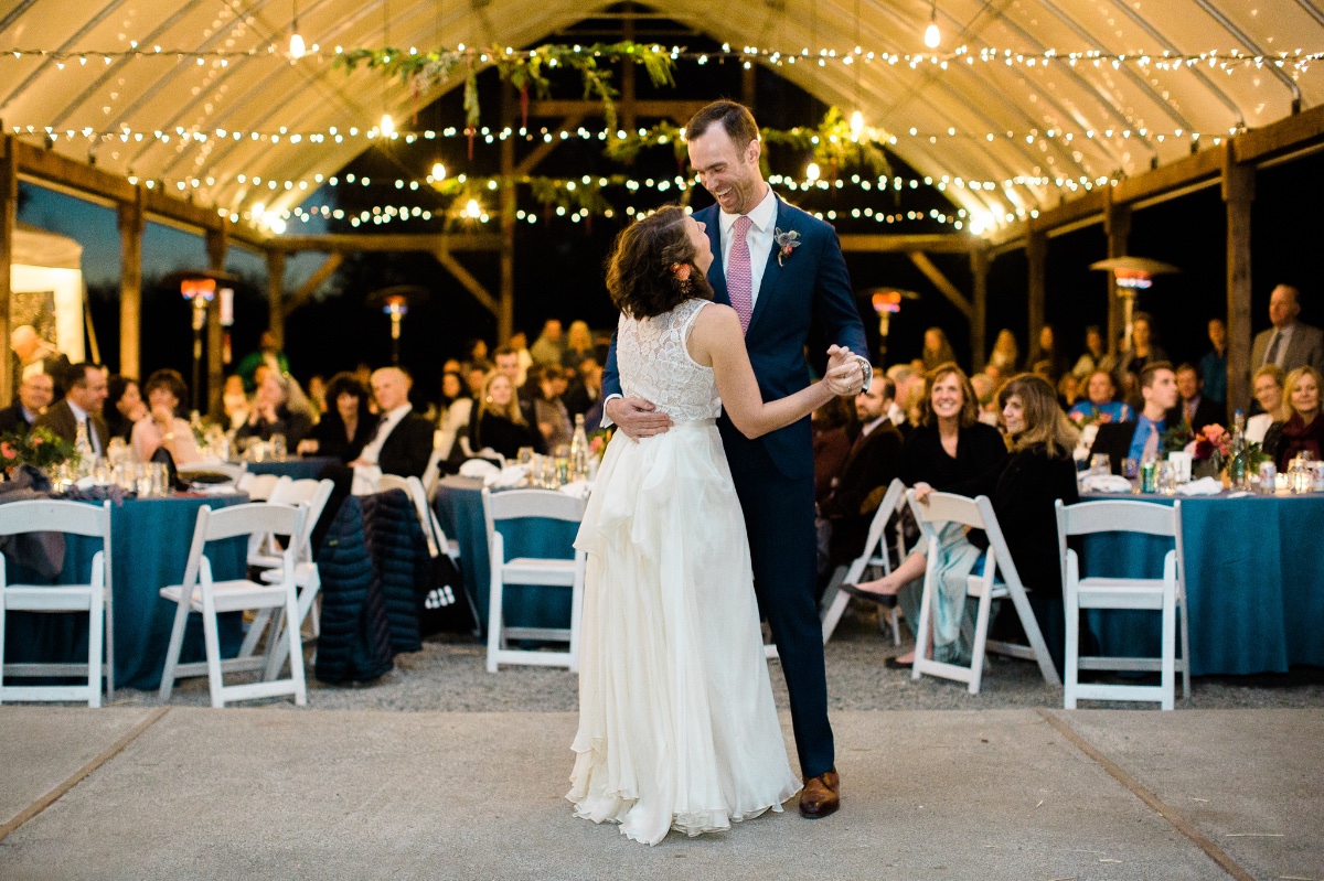 Happy newlyweds share their first dance at a string-lit wedding