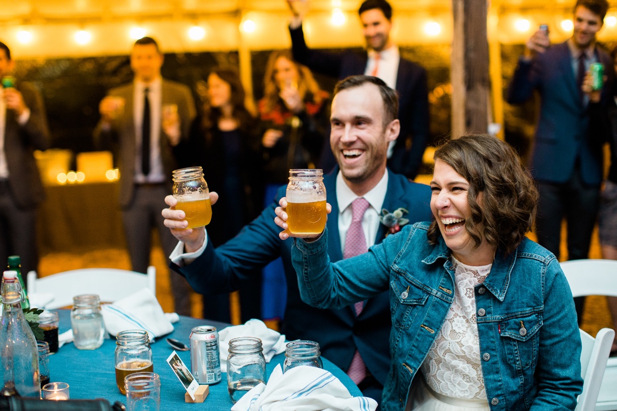 Happy wedding guests toasting with beer in mason jars