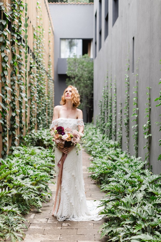 Bride in lace dress with bouquet in a garden setting
