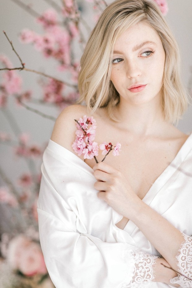Blonde woman in robe holding a cherry blossom branch