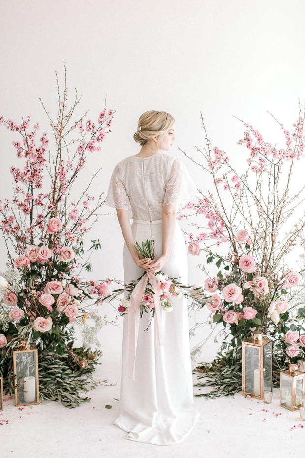 Blonde bride in white gown with floral arrangement