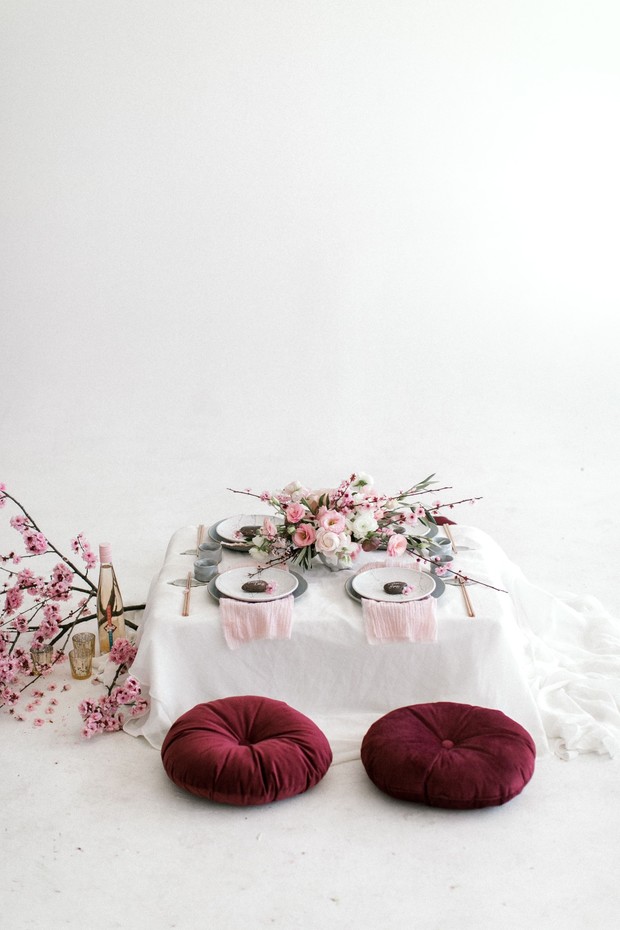 Minimalist table setting with pink flowers and floor cushions