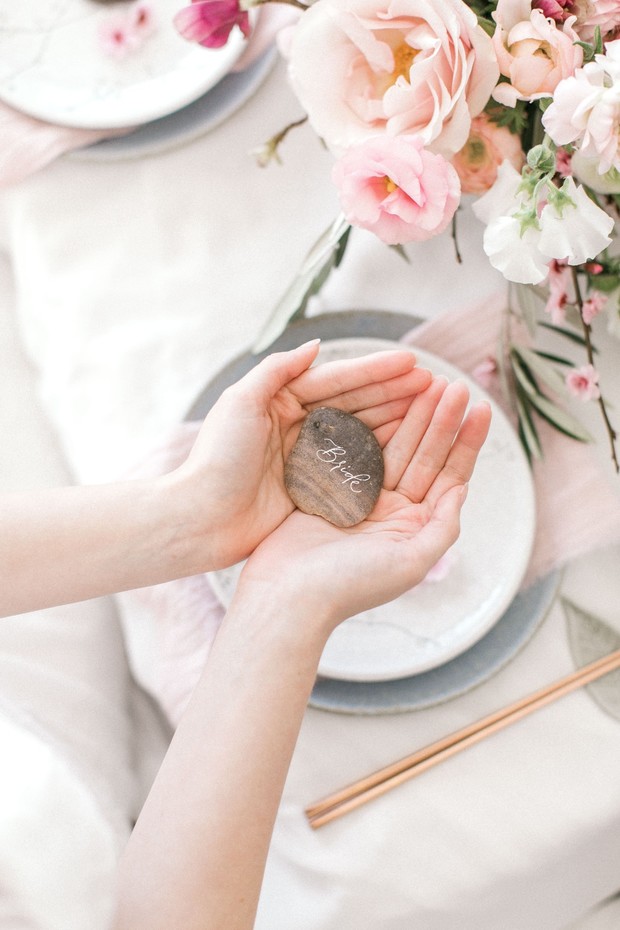 Hands holding a wedding place card rock