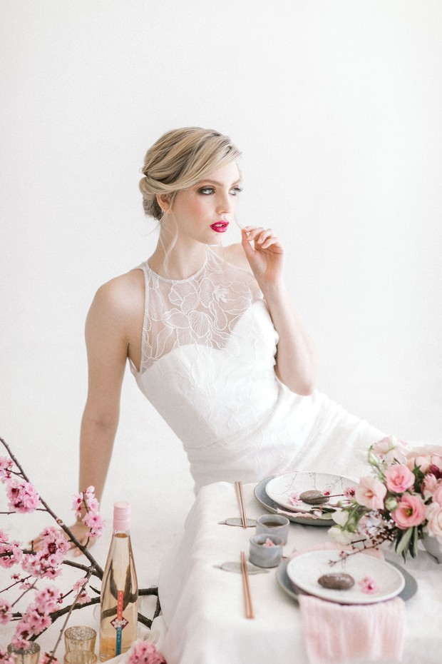 Elegant bride in white lace dress at pink table setting