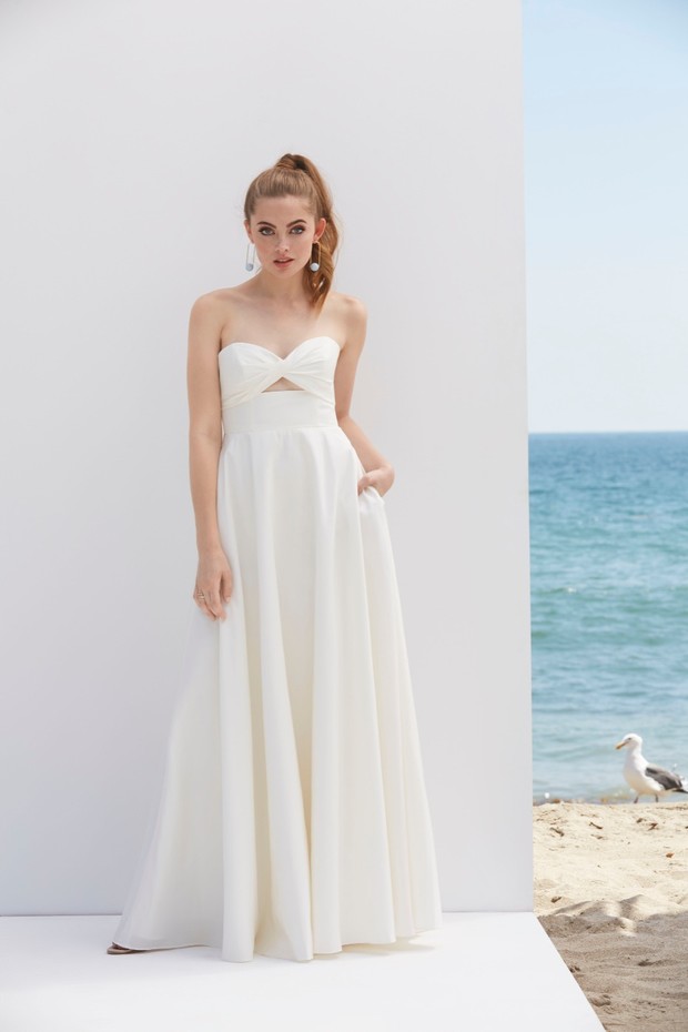 Elegant bride in a white strapless dress on a beach background