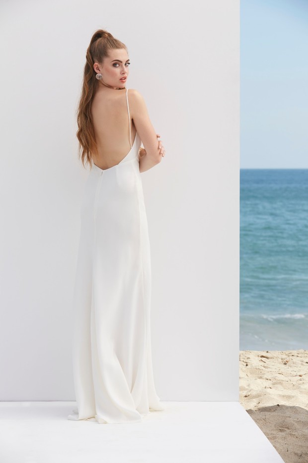 Elegant woman in a white dress looking over her shoulder, beach background