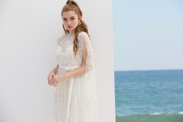 Elegant woman in a wedding dress stands near the sea