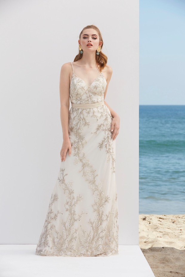 Elegant woman in a white beaded wedding dress near the ocean
