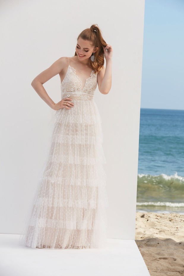 Smiling bride in a tiered wedding dress at the beach