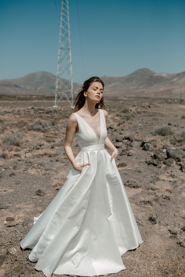 A woman in a white wedding dress standing outside in the desert