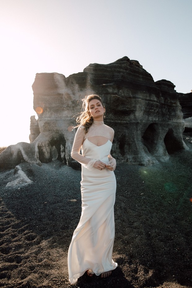 Elegant bride in a white gown posing near dramatic rock formations
