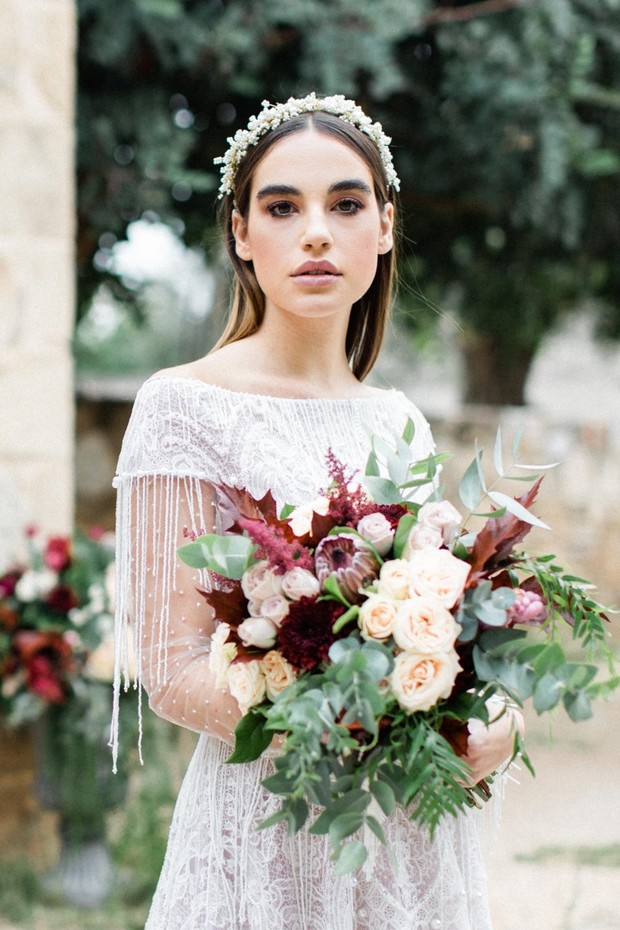 bride in elegant dress with peach and burgundy bouquet