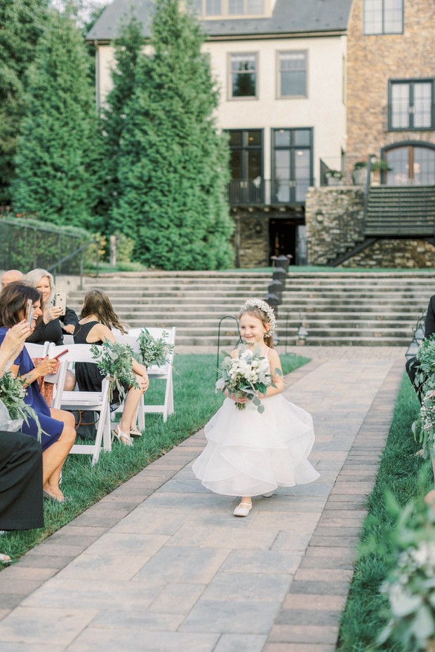 Flower girl walks aisle at outdoor wedding ceremony