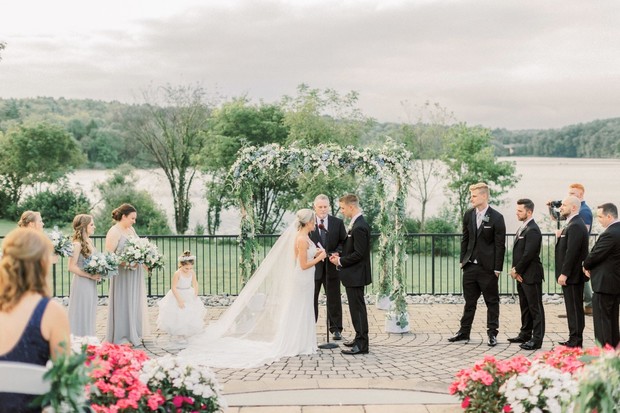 Outdoor wedding ceremony by the lake and floral arch