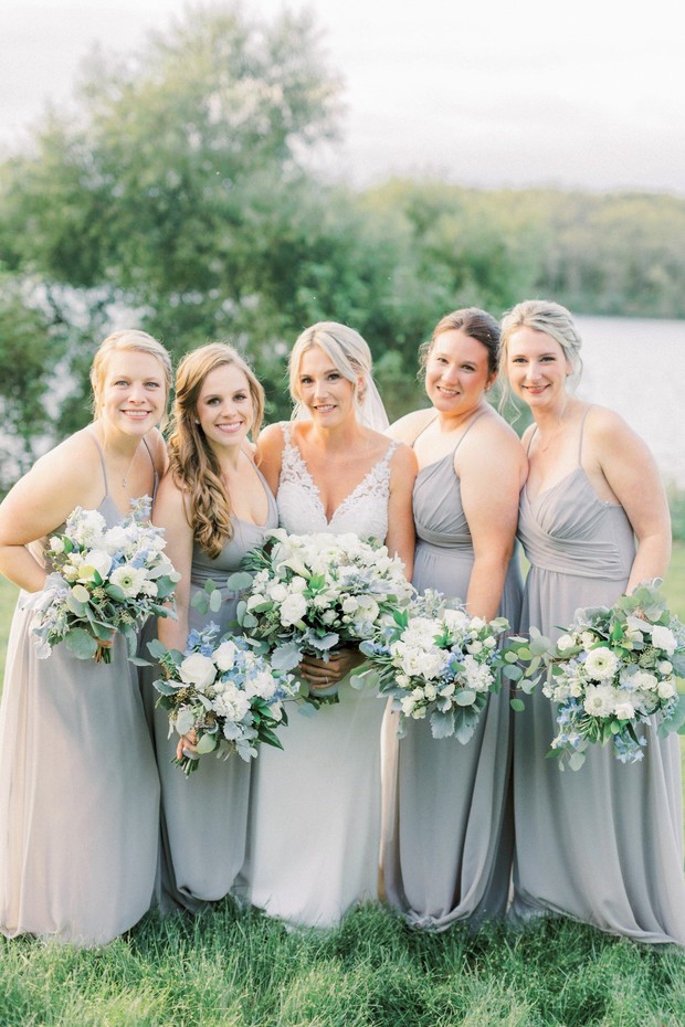 Bride and bridesmaids in gray dresses hold bouquets