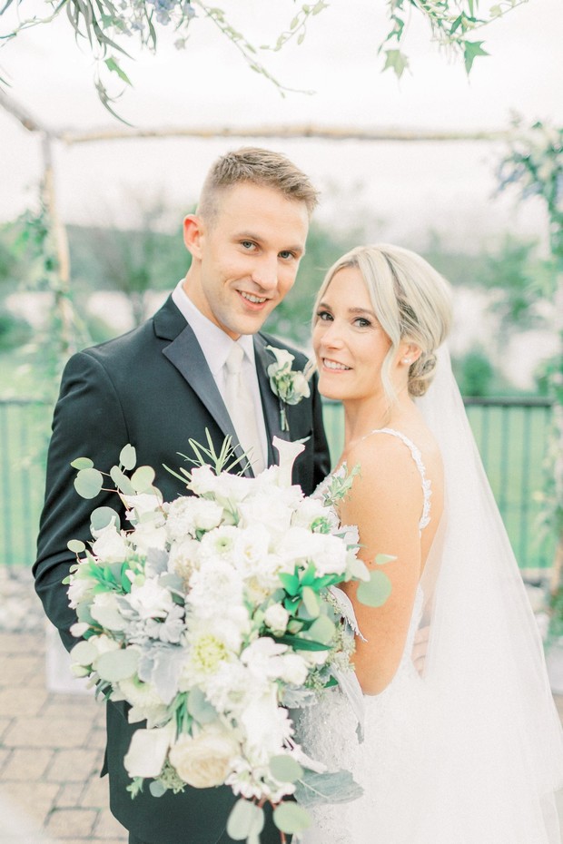 Smiling bride and groom pose at their outdoor wedding ceremony