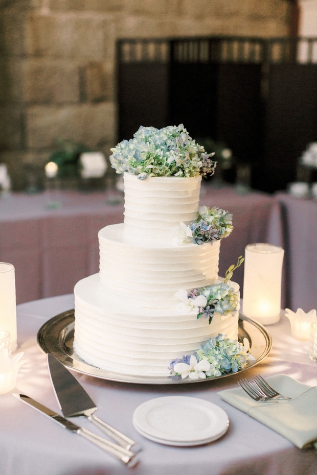 Elegant white wedding cake with blue flower decorations on a table