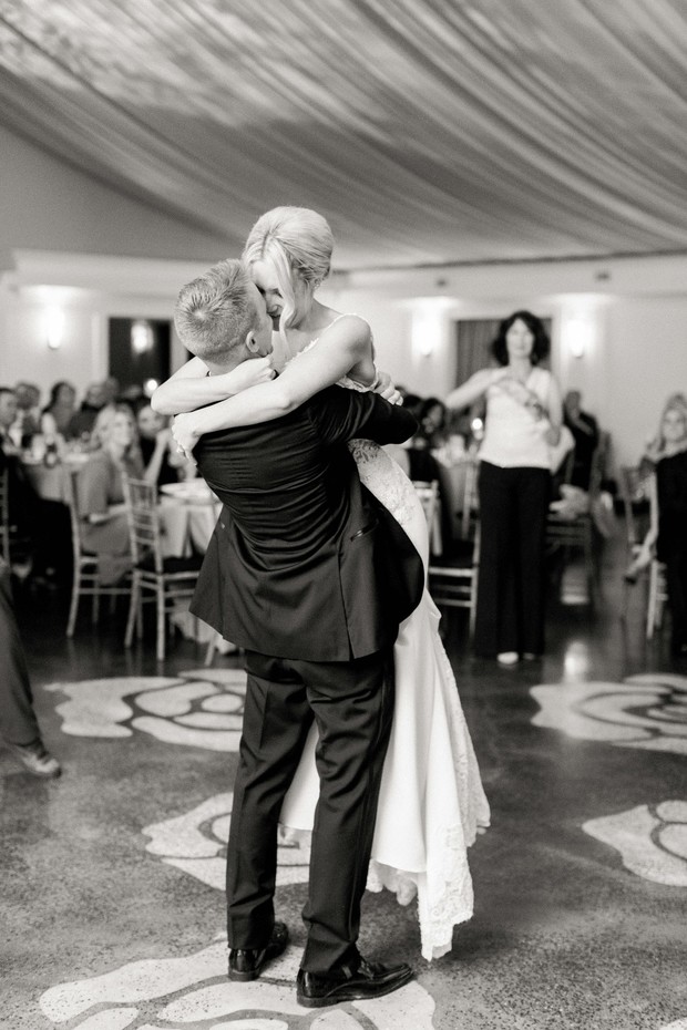 Groom lifts bride on the dance floor during wedding celebration