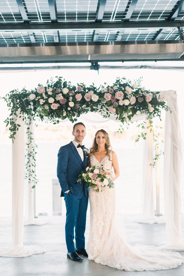 bride and groom with floral accented Chuppah
