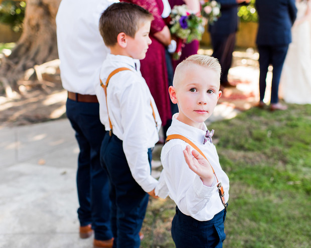 Two young ring bearers pose with suspenders at a wedding ceremony