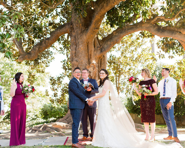 Wedding ceremony under a tree with the happy couple holding hands