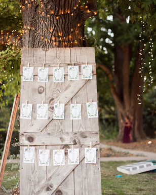 Rustic wedding seating chart on a wooden door with fairy lights