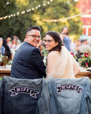 Two smiling brides at their wedding, with Wifey jackets