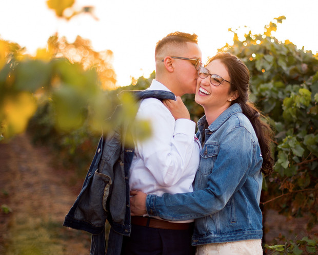 Happy couple shares a loving moment, kissing in a vineyard