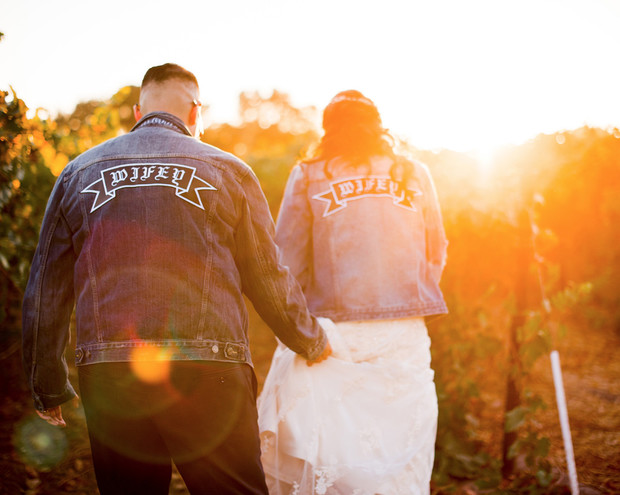 Newlyweds in denim jackets with wifey at a golden hour wedding