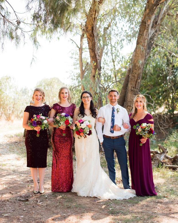 Wedding party posing together under the tree, happy smiles abound