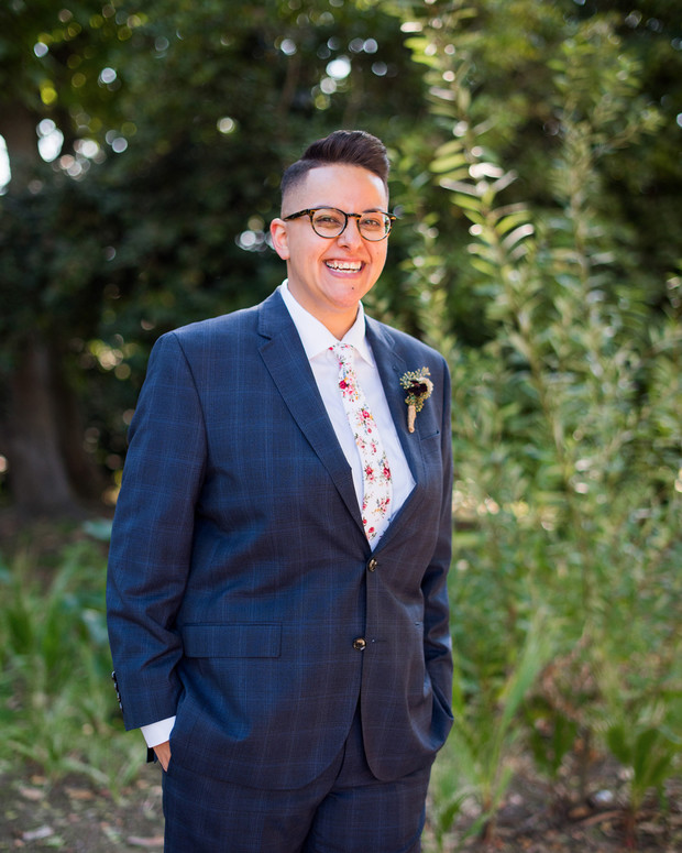 Stylish person smiling in a blue suit with floral tie