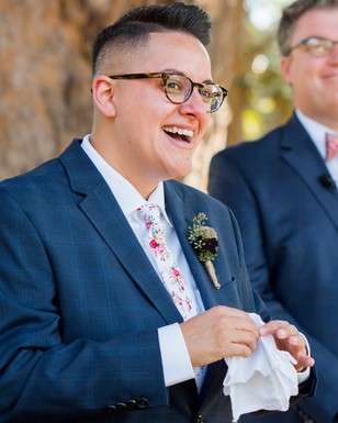 Smiling person in a blue suit at an outdoor wedding