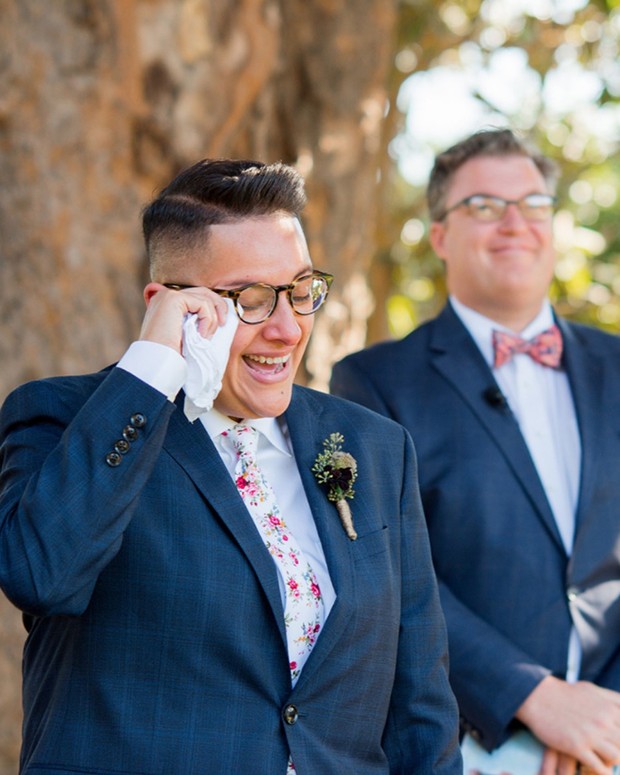 Groom wipes tears of joy during wedding ceremony, smiling, emotional
