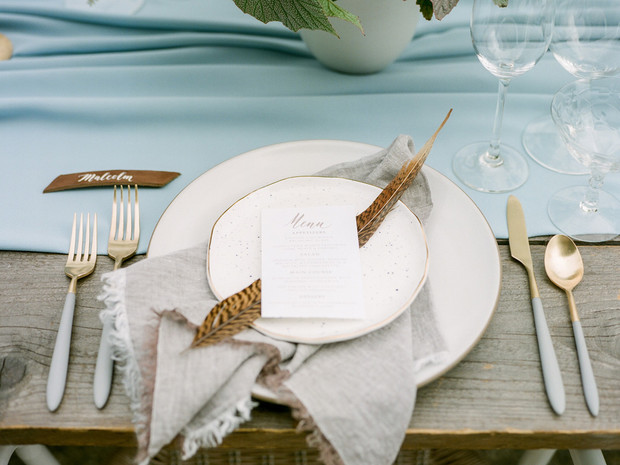 Elegant table setting with feather decor and menu on a wooden table