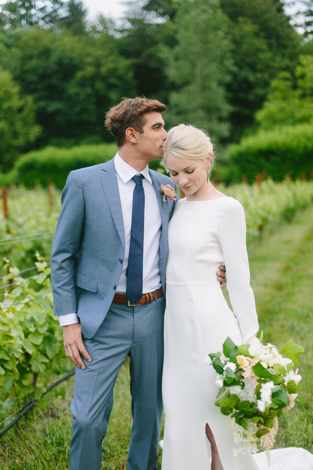 Groom kisses bride on the forehead at vineyard wedding