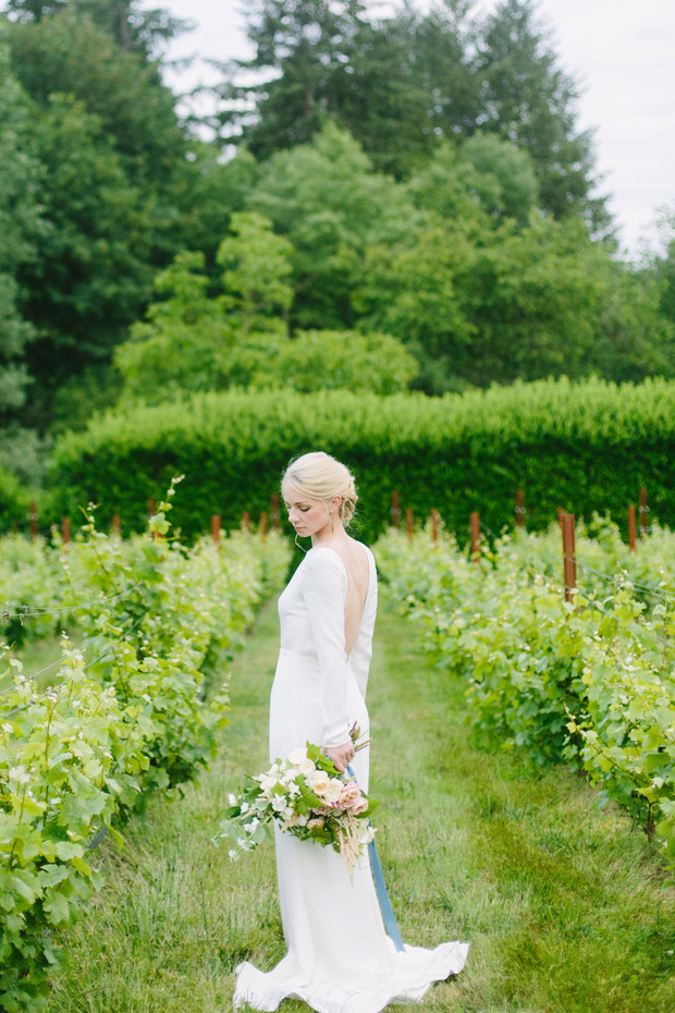 Bride in a white dress holding bouquet in the vineyard