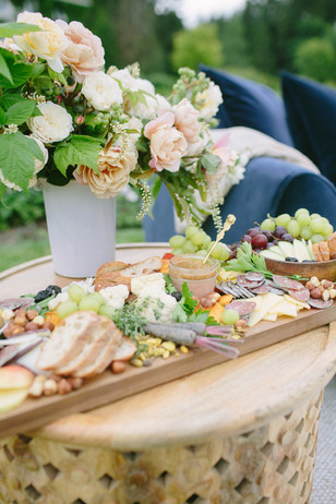 Delicious charcuterie board with flowers for an outdoor gathering
