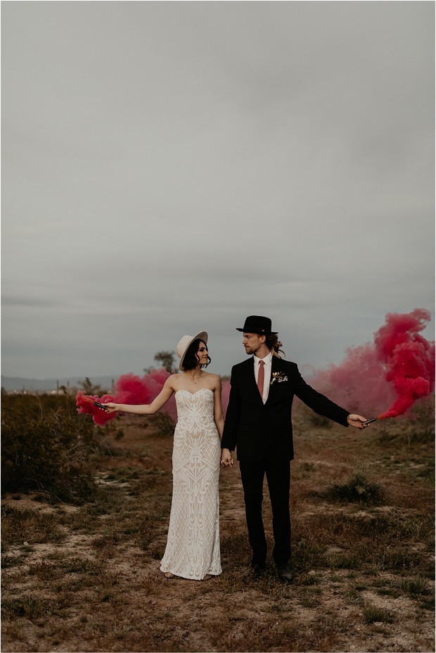hipster couple in the desert with red smoke bombs