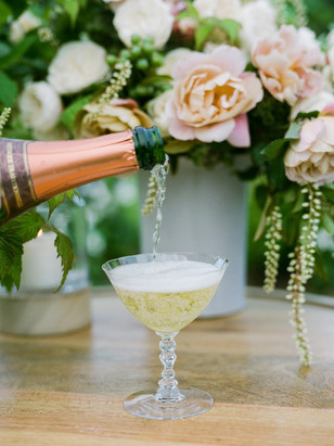 Champagne being poured into a glass, with flowers in the background