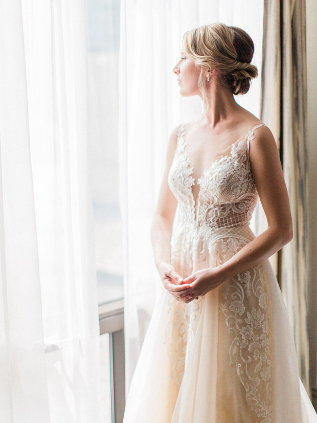 Bride in wedding dress looks out the window, beautiful gown