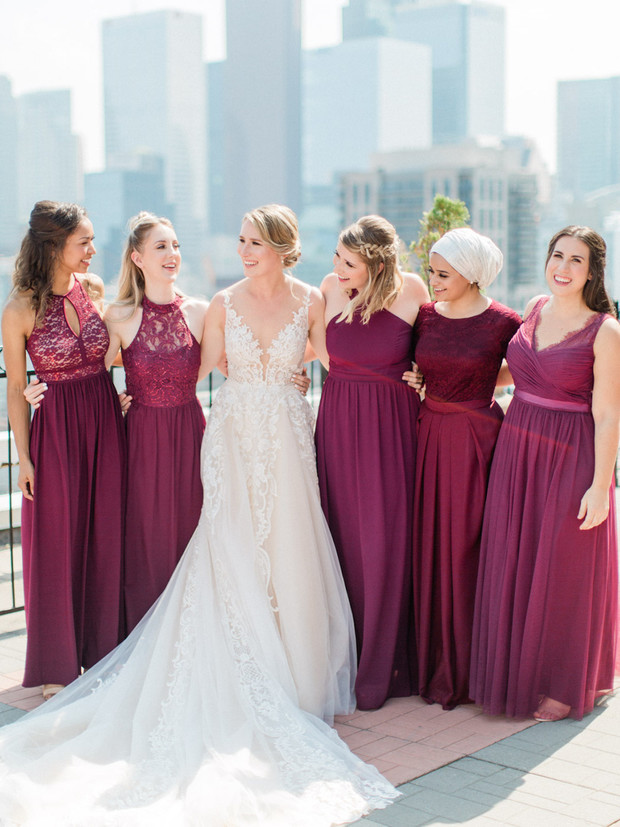 Bride and bridesmaids smiling at a wedding, dresses in burgundy