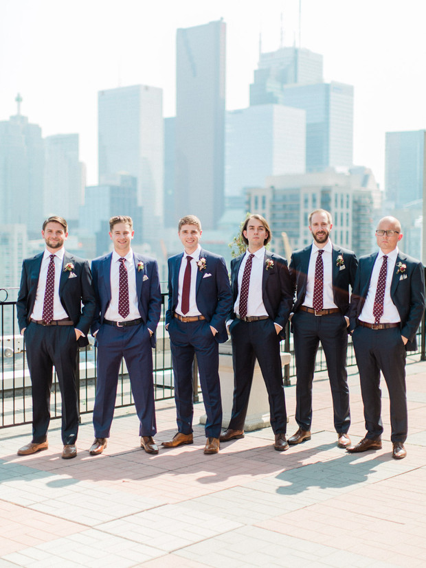 Groomsmen posing in front of a city skyline on a sunny day